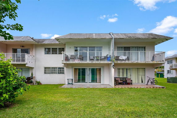 Rear view of a two-story house with balconies and sliding doors.