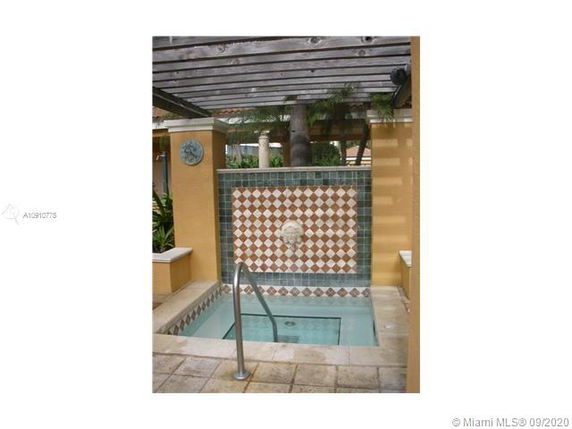 Small outdoor area with a tiled spa or small pool featuring a decorative fountain wall and pergola.
