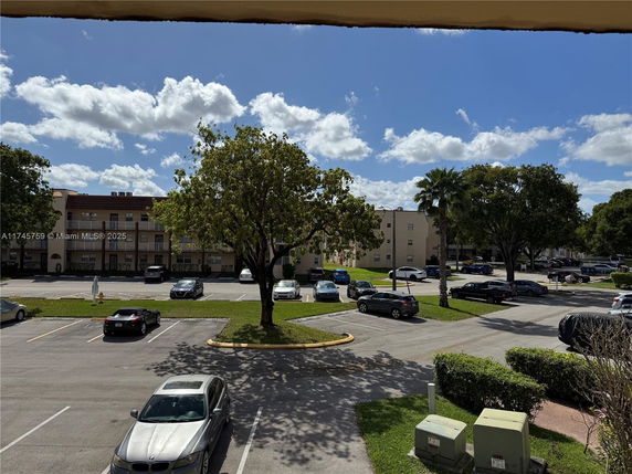 View of a parking area with several cars parked near apartment buildings.