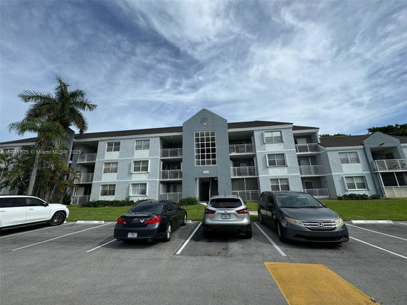 Front view of a multi-story residential building with parking area.