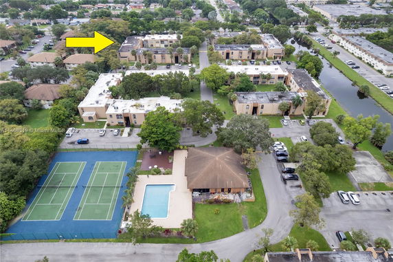 Aerial view of a residential complex with multiple apartment buildings, a swimming pool, and tennis courts.