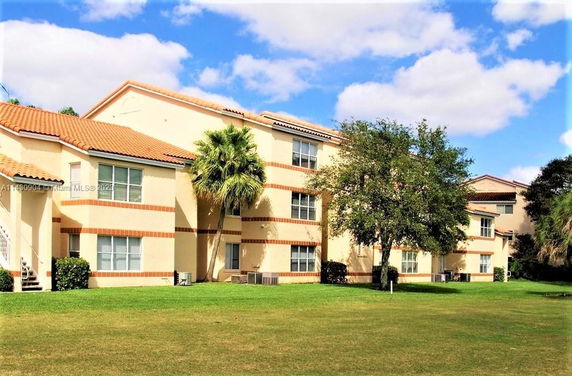 Front view of a multi-story residential building with tan walls and red tiled roof.