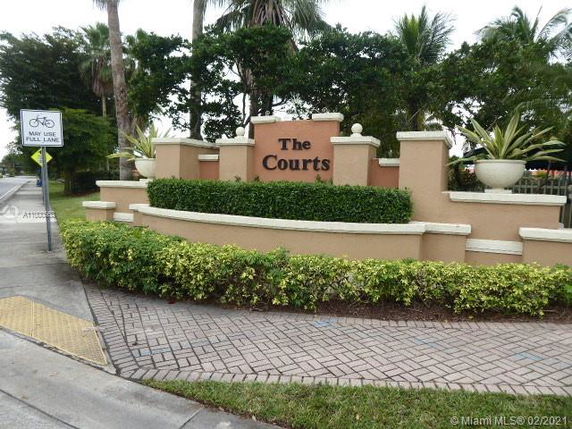 Entrance signage of The Courts residential area with landscaped greenery.