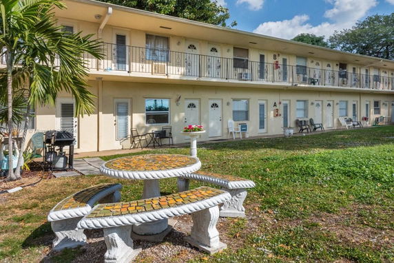 Front view of a two-story building with balconies and a small patio area with seating.