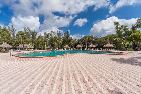 Outdoor swimming pool with surrounding lounge chairs and trees.