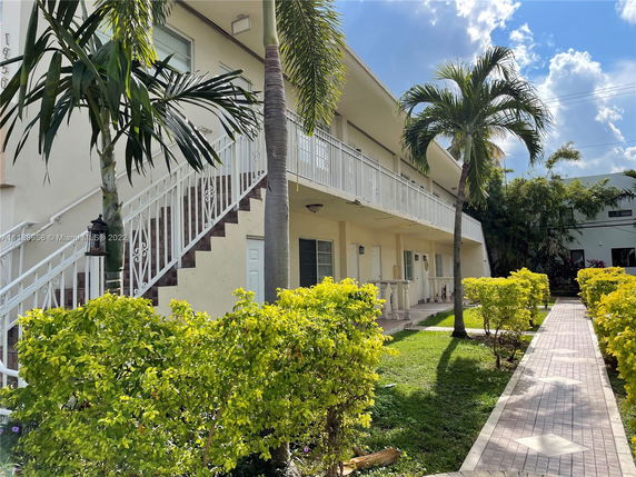 Front view of a two-story building with external stairs and a walkway.
