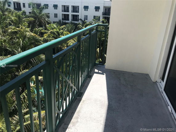 Balcony view overlooking palm trees and adjacent buildings.