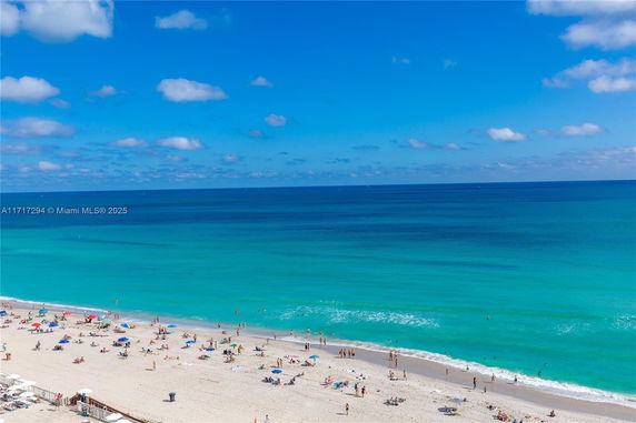 Panoramic view of a beach with people on the sand and swimming in the ocean.