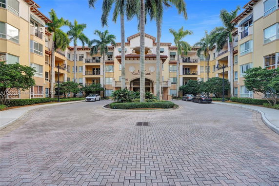 Front view of a four-story residential building with palm trees.
