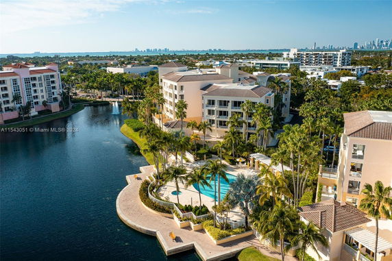 Aerial view of a waterfront residential complex with multiple multi-story buildings and a pool area.
