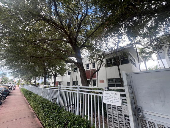 Front view of a multi-story condominium building with large windows and a gated entrance.