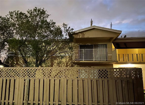 Front view of a two-story building with a balcony and a lattice fence.