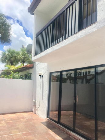 Exterior view of a two-story building with a balcony and sliding glass doors.