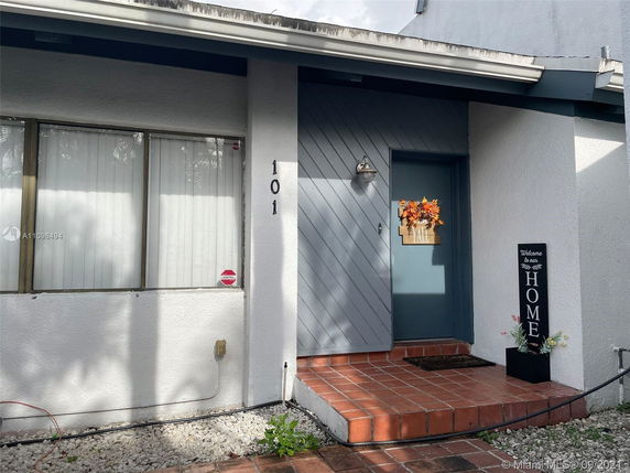 Front view of a house with a blue door and a welcome sign.