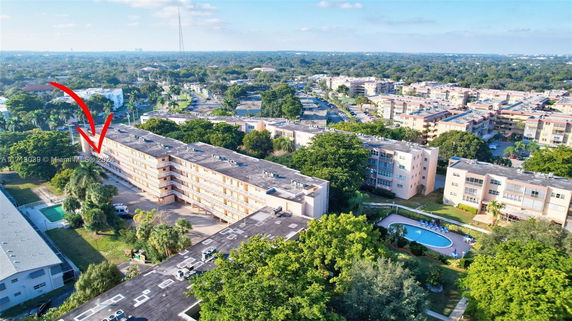 Aerial view of a residential area with mid-rise apartment buildings surrounded by trees and greenery.