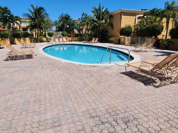 Outdoor swimming pool area with surrounding lounge chairs and palm trees.