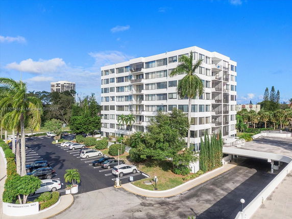 Front view of a multi-story apartment building with parking area.