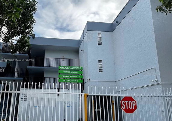 Front view of a multi-story condominium building with a gated entrance.
