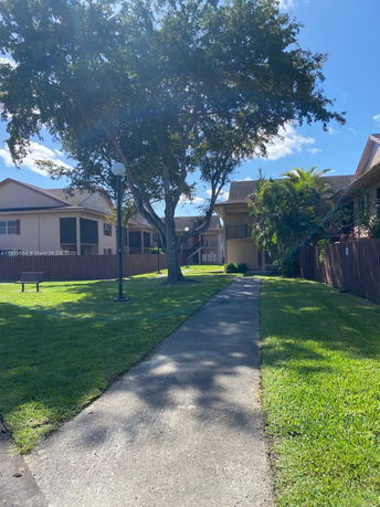 Pathway between residential buildings with trees and grass.