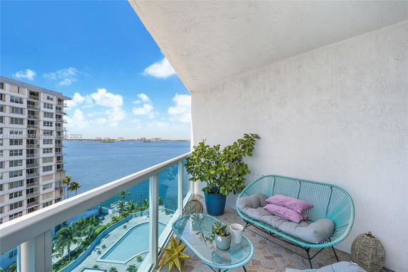 Balcony with seating overlooking a water view and adjacent building.