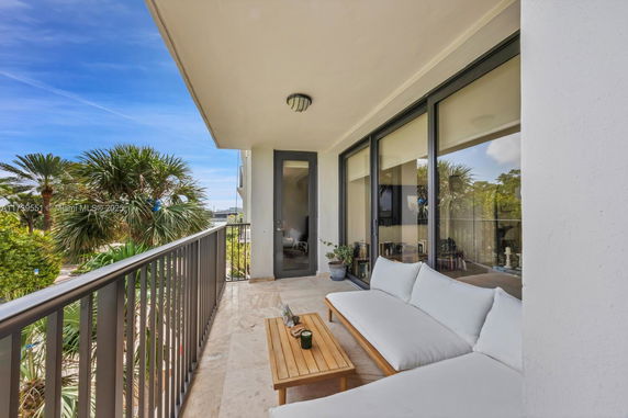 Balcony view with outdoor seating and a view of trees.