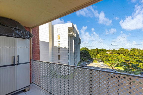 Balcony view overlooking a parking area and surrounding greenery.