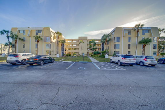 Front view of a multi-story residential building with parking area.