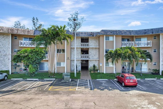 Front view of a three-story apartment building with balconies and parking lot.