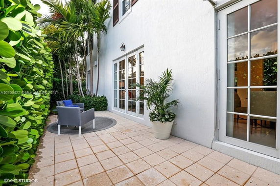 Front view of a house with large glass doors and a tiled patio area.