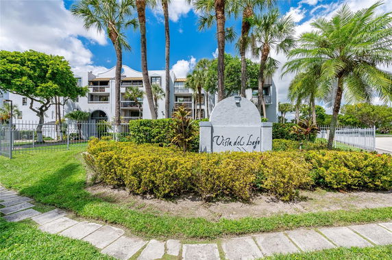 Front view of a multi-story building with balconies surrounded by palm trees.