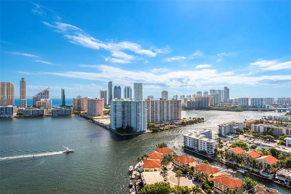 Panoramic view of high-rise buildings along a waterfront, with skyscrapers in the background.