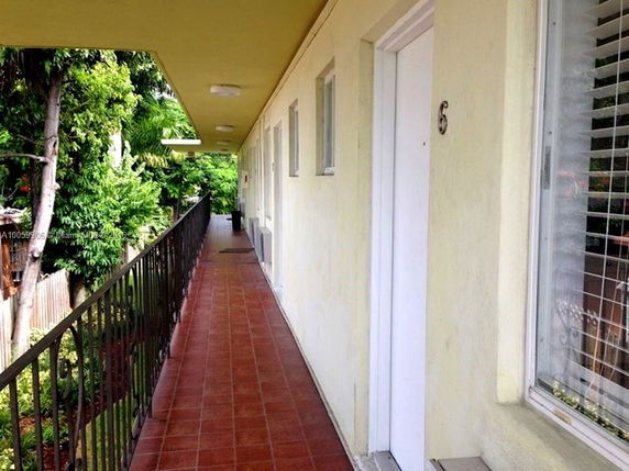 Exterior corridor of a building with doors and windows leading to individual units.