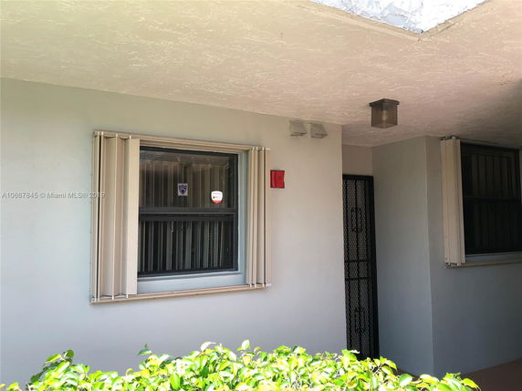 Exterior view of a building entrance with security bars on windows.