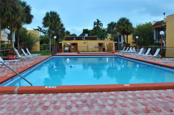 Outdoor swimming pool with surrounding lounge chairs in a residential area.