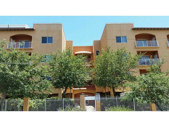 Front view of a multi-story apartment building with balconies and a gated entrance.