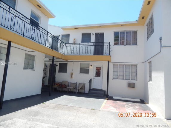 Front view of a two-story building with balconies and a small entrance area.