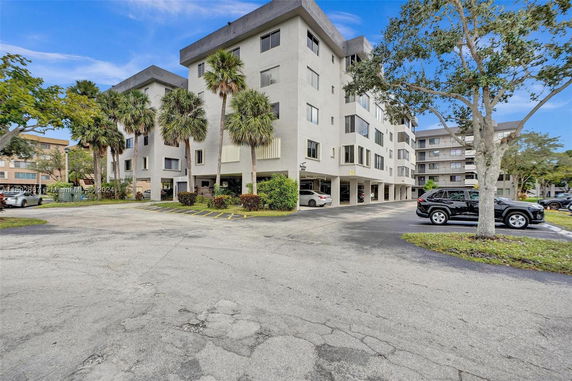 Front view of a multi-story residential building with parking area.