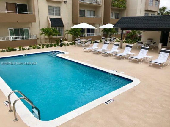 Image of an outdoor swimming pool surrounded by lounge chairs and umbrellas.