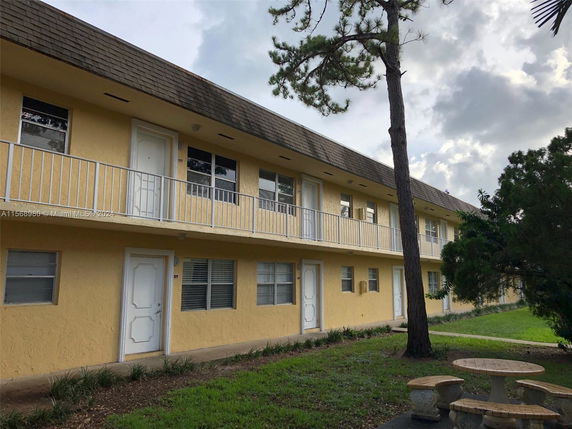 Front view of a two-story building with a balcony and yellow exterior.
