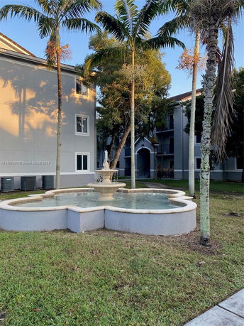 Front view of a multi-story building with a decorative fountain and palm trees.