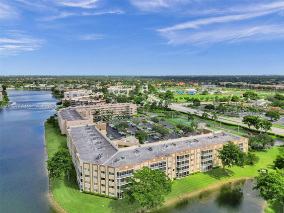 Panoramic view of residential buildings and surrounding landscape with a water body adjacent to the structures.