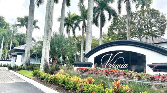 Entrance to a residential community with a sign reading 'Valencia' and landscaping.