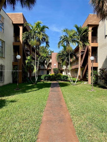 Outdoor view of a multi-story residential building with balconies and palm trees.