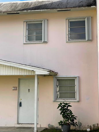 Front view of a two-story house with three windows and a small covered entryway.