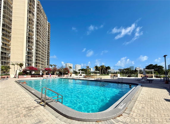 Outdoor swimming pool area with high-rise buildings in the background.