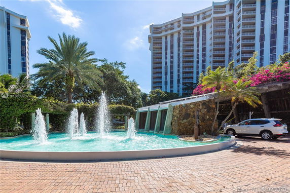 Front view of a multi-story residential building with a water fountain in the foreground.