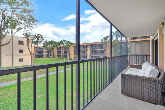 View from a balcony overlooking a residential area with buildings and green lawn.