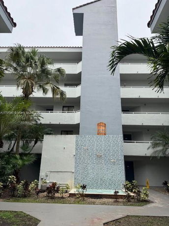 Front view of a multi-story building with balconies and a central column.