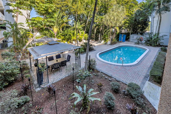 Outdoor swimming pool area with surrounding vegetation and a patio seating area.
