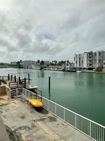 Waterfront view with buildings, jet ski, and moored boat along the dock.